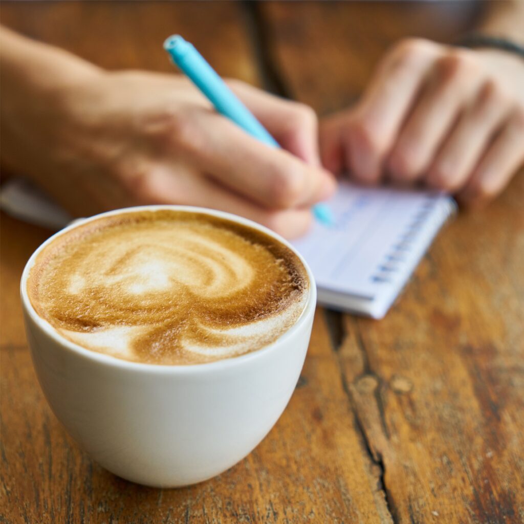 Tasse Kaffee neben Notizblock – Symbol für kreative Pausen und inspirierende Gespräche.