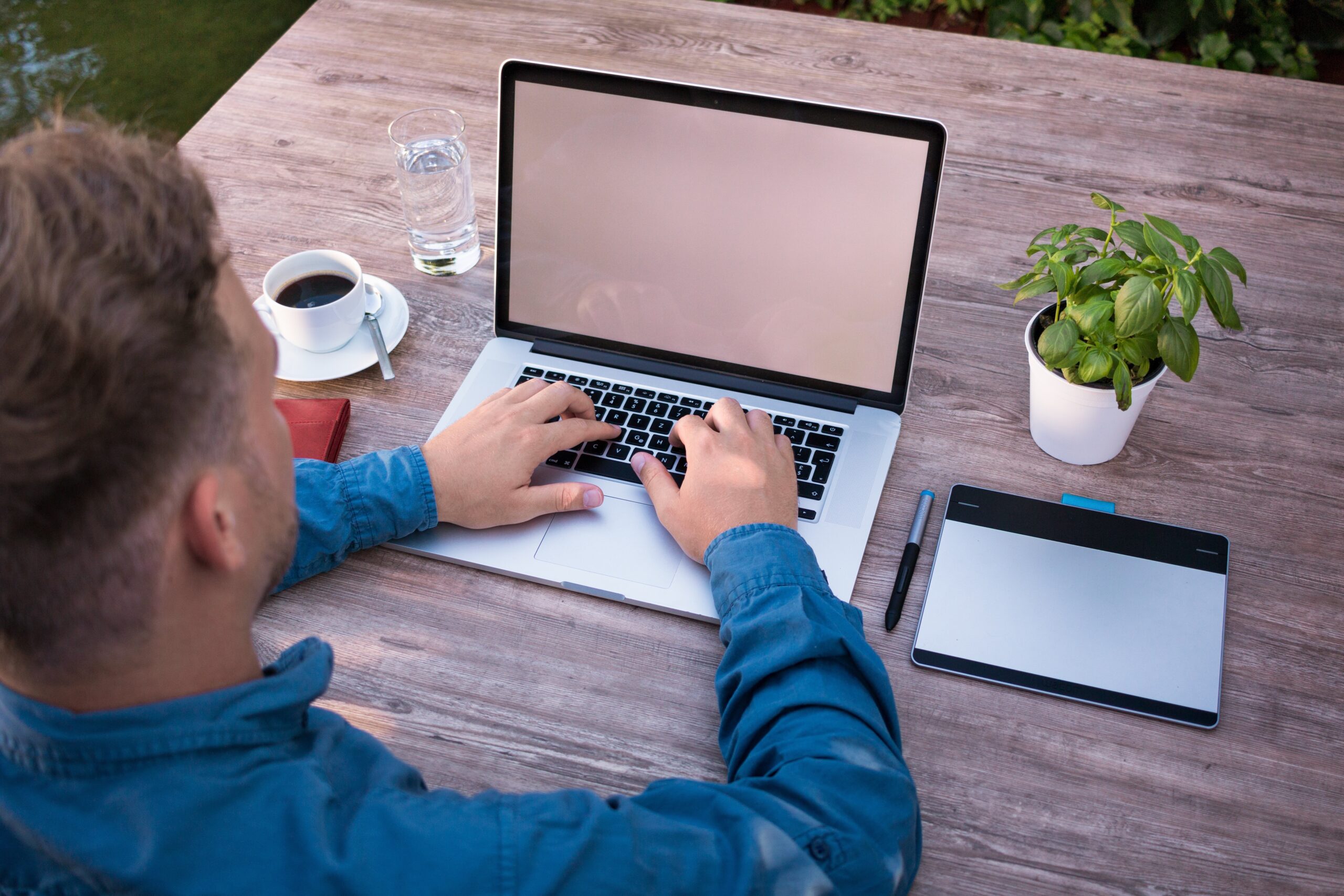 Person arbeitet am Laptop im Freien, Symbol für konzentriertes Lernen und Wissensarbeit